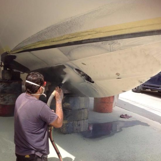 Technician removing bottom paint from a boat hull